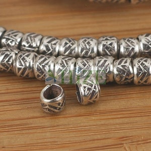 May include: Silver metal beads with a geometric pattern. The beads are strung together to form a necklace or bracelet. The beads are about 1 cm in diameter.