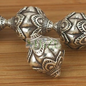 May include: Close-up of three silver beads with intricate floral designs. The beads are round and have a textured surface.