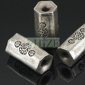 May include: Three silver hexagonal beads with a decorative floral pattern. The beads are approximately 1 inch in length.