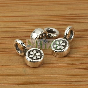 May include: Three silver-toned metal charms with a flower design. Each charm has a small loop for attaching to a bracelet or necklace.