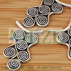 May include: Two silver metal decorative pieces with a swirling design. Each piece has a series of connected spirals.