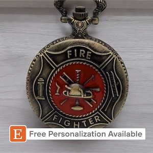 May include: A gold-tone pocket watch with a red and black firefighter emblem. The watch face reads "FIRE FIGHTER".