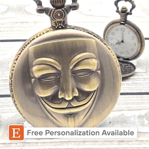 May include: A bronze-colored pocket watch with a smiling mask design on the front. The watch has a detailed, vintage aesthetic. A second, smaller pocket watch is visible in the background. The text "Free Personalization Available" is in the lower left corner.