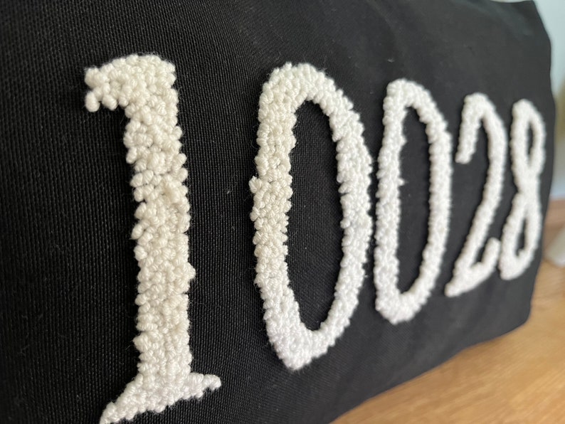 May include: Black canvas tote bag with the number 1028 embroidered in white yarn.