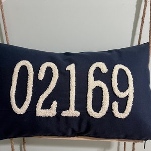 May include: A navy blue pillow with the number 02169 embroidered in white.