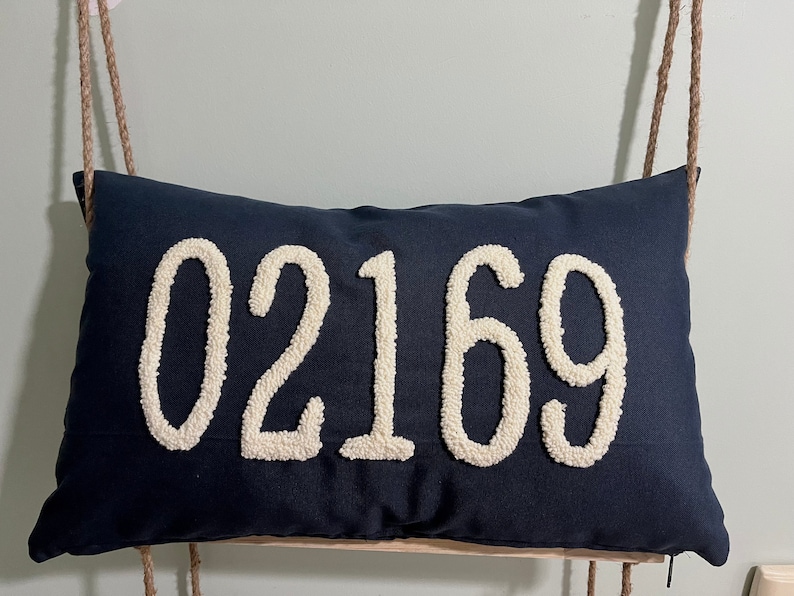 May include: A navy blue pillow with the number 02169 embroidered in white.
