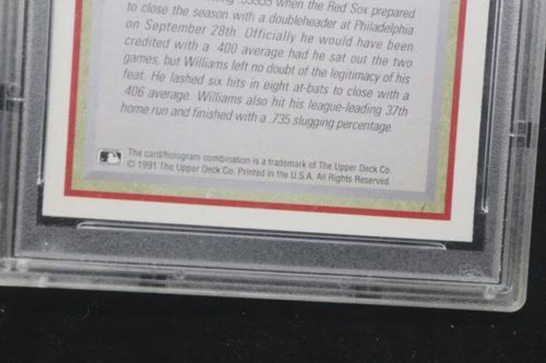 May include: A baseball card encased in a clear plastic holder. The card has text in black font on a white background with a red border. The Upper Deck Co. trademark is visible.