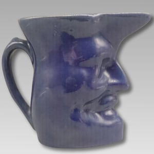 May include: A white ceramic mug with a black handle and the text "But First, Coffee" in a black, handwritten-style font. The mug is on a white surface.