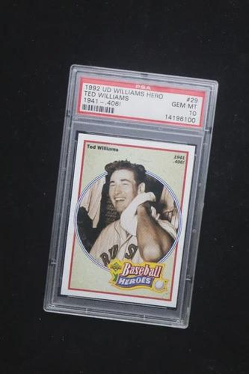 May include: A 1992 Upper Deck Ted Williams baseball card, encased in a protective holder. The card features a portrait of Ted Williams and the text "Baseball Heroes". The holder has a PSA label with details.