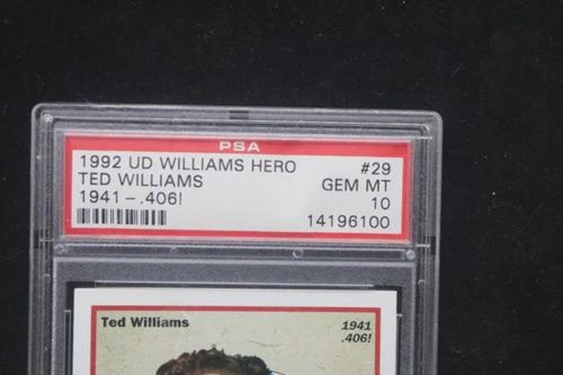 May include: A graded trading card encased in a clear plastic holder. The card features text that reads "1992 UD WILLIAMS HERO TED WILLIAMS 1941-.406!" and "#29 GEM MT 10". The card is a collectible item.