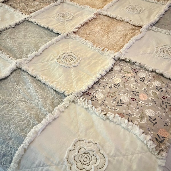 Modern rag quilt with all-cotton, 12-inch squares in neutral colors embellished with appliqued and embroidered flowers.