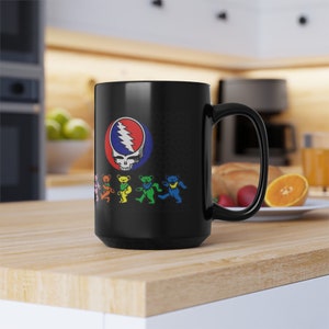 May include: Black ceramic mug with a colorful graphic of a skull with a lightning bolt and dancing bears. The bears are in a rainbow color scheme.