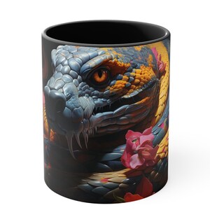 Peut inclure: Une tasse à café noire avec une image colorée d'un serpent enroulé autour de fleurs roses. Le serpent a un corps bleu et jaune avec un œil orange vif.