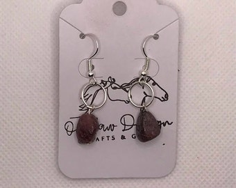 May include: A pair of silver earrings with small, dark red stone drops. The earrings are on a white card with the text "Paw Design Crafts & Gifts".