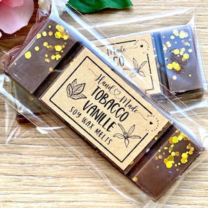 May include: Handmade tobacco and vanilla soy wax melts in a clear plastic package. The dark brown wax bars are decorated with gold glitter. The label reads "Hand Made Tobacco Vanille Soy Wax Melts."