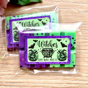 May include: Two green and purple soy wax melts with a witch theme. The label says "Witches Brew Soy Wax Melts" with a witch and cauldron graphic. The melts are packaged in a clear plastic bag.