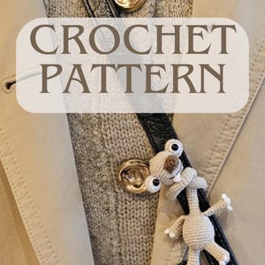 Op de afbeelding: Een beige trenchcoat met een zwarte leren riem en gouden knopen. Een kleine, gehaakte luiaard is aan de riem bevestigd. De tekst "CROCHET PATTERN" staat over de afbeelding.