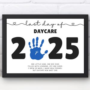 Op de afbeelding: Een ingelijste print met de tekst "last day of DAYCARE 2025". Het ontwerp bevat een blauwe handafdruk en een gedicht over de kinderopvang. De lijst is zwart en de achtergrond is wit.