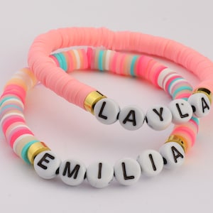 May include: Two colourful beaded bracelets with the names "Layla" and "Emilia" spelled out in white letters.