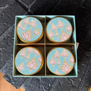 May include: Set of four round, gold-rimmed containers with blue and pink floral designs. The containers are arranged in a square box.