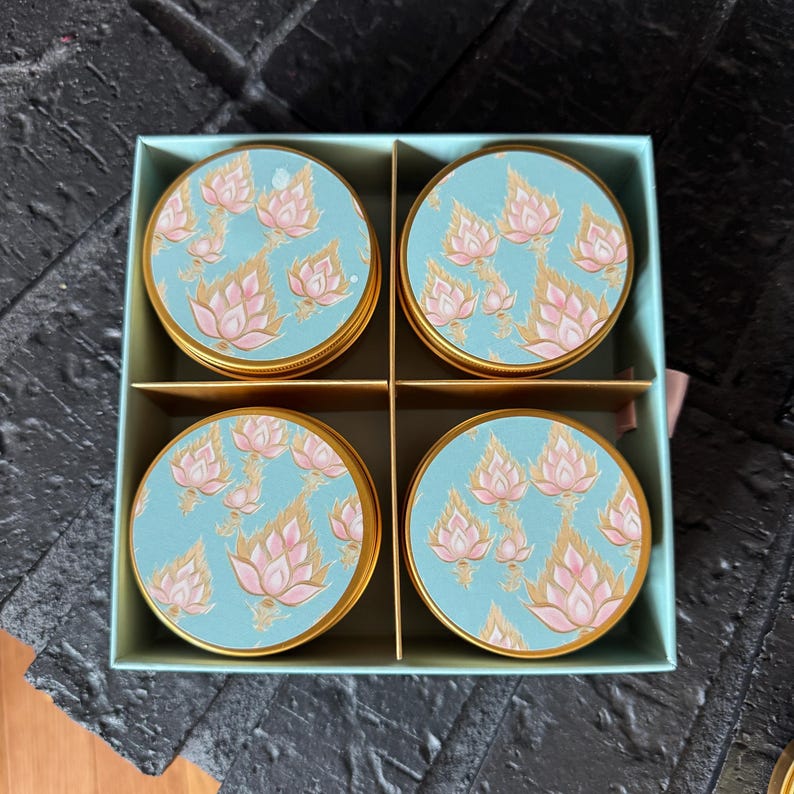 May include: Set of four round, gold-rimmed containers with blue and pink floral designs. The containers are arranged in a square box.
