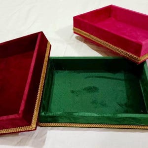 May include: Three velvet trays with gold trim. The trays are red, green, and pink.