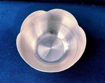 May include: A silver metal bowl with a scalloped edge. The bowl has a shiny, brushed finish.