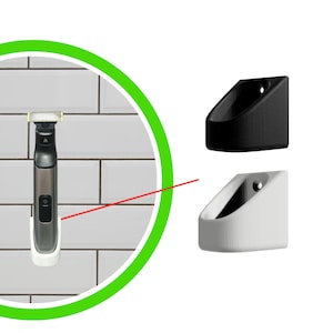 Può includere: Un rasoio elettrico bianco e nero è montato su una parete di piastrelle bianche con un supporto a parete bianco e nero. Il supporto a parete è progettato per tenere il rasoio in posizione verticale.