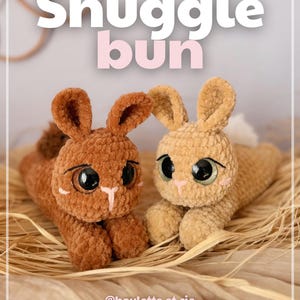 Può includere: Due coniglietti all'uncinetto, uno marrone e uno beige, con grandi occhi e dettagli rosa. Il testo "Snuggle bun" è visibile sopra. L'immagine include anche il testo "@boulette.et.cie" e "© 2026 Boulette & Cie".