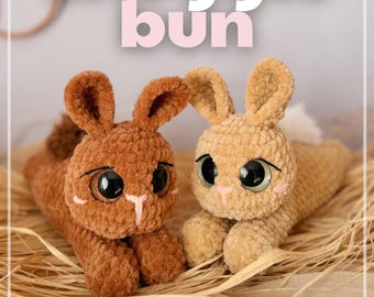 Può includere: Due coniglietti all'uncinetto, uno marrone e uno beige, con grandi occhi e dettagli rosa. Il testo "Snuggle bun" è visibile sopra. L'immagine include anche il testo "@boulette.et.cie" e "© 2026 Boulette & Cie".