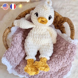 May include: A handmade, white crochet duckling toy with a yellow beak and feet, nestled in a woven basket atop a pink blanket. The text "PDF PATTERN" is visible in the image. The duckling is a soft, plush creation.