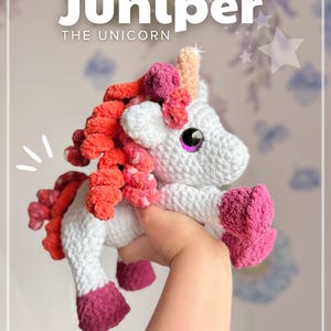 Może przedstawiać: Ręcznie robiona szydełkowa zabawka jednorożca o imieniu "Juniper". Biały jednorożec ma różową i pomarańczową grzywę, różowe kopyta i jasno pomarańczowy róg. Tekst "Juniper THE UNICORN" znajduje się na górze obrazu, z uchwytem Instagram @boulette.et.cie na dole.