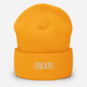 Puede incluir: Un gorro amarillo brillante con la palabra "CREATE" bordada en blanco en la parte delantera.