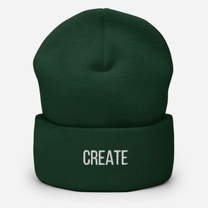 Puede incluir: Un gorro de lana verde oscuro con la palabra "CREATE" bordada en blanco en la parte delantera.