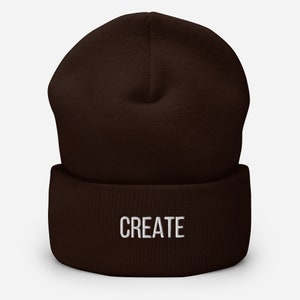 Puede incluir: Un gorro marr&oacute;n con la palabra "CREATE" bordada en blanco en la parte delantera.