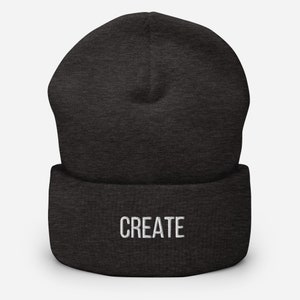 Puede incluir: Un gorro de lana gris oscuro con la palabra "CREATE" bordada en blanco en la parte delantera.