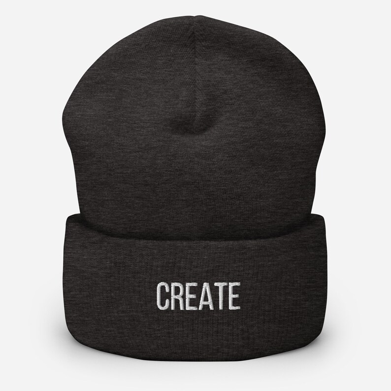 Puede incluir: Un gorro de lana gris oscuro con la palabra "CREATE" bordada en blanco en la parte delantera.