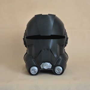 May include: A black plastic helmet with a visor and two round details on the front. The helmet is designed to resemble a futuristic soldier's helmet.