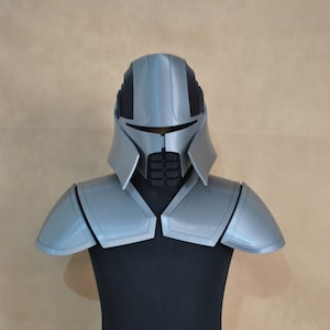 May include: A 3D printed silver and black helmet with shoulder pads and a copper belt with red accents. The helmet has a visor and a black face mask. The belt has the letters "TIT" on it.