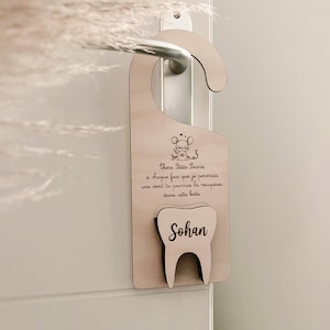 Puede incluir: Un colgador de puerta de madera para la hada de los dientes con una ilustración de ratón y el texto "Chère Petite Souris, à chaque fois que je perdrais une dent tu pourras la récupérer dans cette boîte" y el nombre "Sohan" escrito en un diente.