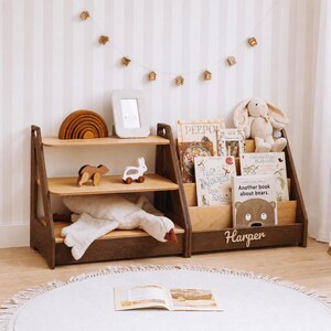 May include: A wooden toy storage unit with three shelves and a book display section. The unit features a dark brown frame with light wood shelves. The name Harper is displayed in white script on the front. It holds books, a plush rabbit, and toys.