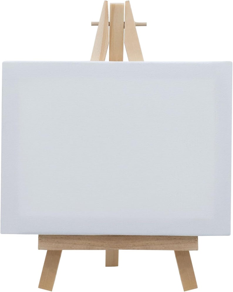 May include: A small wooden easel with a white canvas. The easel has a simple design with three legs and a rectangular base.