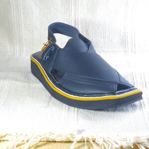 May include: A navy blue sandal with a strap and buckle closure. The sandal has a black sole with a yellow and white trim. The shoe is made of leather-like material and is designed for comfort and style.
