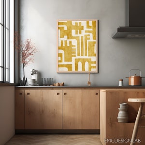 May include: A kitchen with wooden cabinets and a large abstract painting in a light wood frame. The painting is in shades of yellow and white and features geometric shapes.
