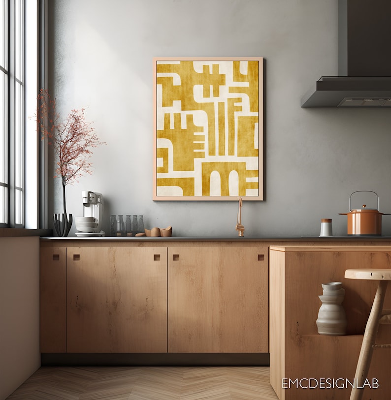 May include: A kitchen with wooden cabinets and a large abstract painting in a light wood frame. The painting is in shades of yellow and white and features geometric shapes.