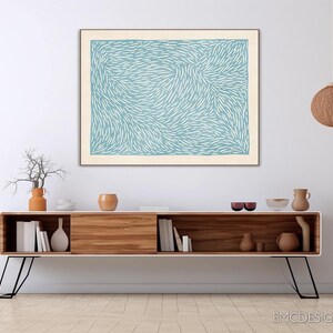 May include: A rectangular wall art print featuring a light blue background with a dense pattern of short, white, curved, dash-like marks. The artwork is framed in a thin, light-coloured wood frame and is displayed horizontally on a plain wall.