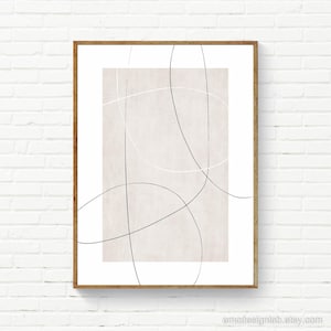 May include: A framed wall art print featuring a rectangular beige centre panel on a white background. The composition is overlaid with thin, intersecting black and white continuous lines that form curved, abstract shapes across the surface.
