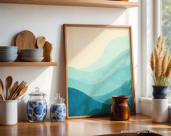 May include: A framed wall art print featuring abstract, layered wavy shapes in shades of cream, light mint, teal, and deep blue. The rectangular artwork is displayed in a thin wooden frame, showcasing a smooth, gradient-like color transition.