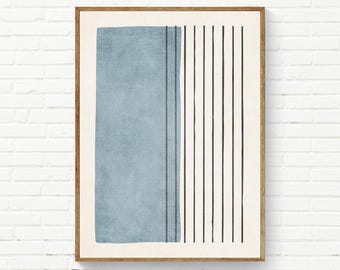 Op de afbeelding: Een ingelijste muurkunstprint met een groot, getextureerd, stoffig blauw rechthoekig blok aan de linkerkant, gecontrasteerd door een reeks dunne, verticale zwarte lijnen aan de rechterkant, alles tegen een effen gebroken witte achtergrond.