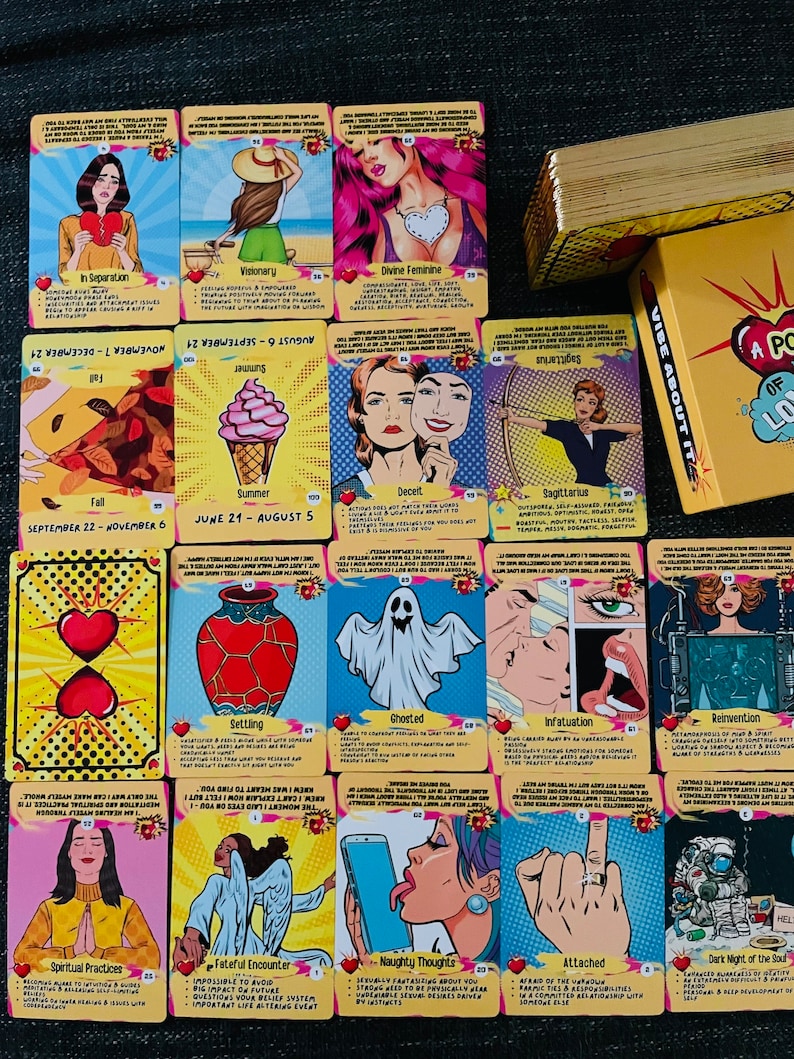 Peut inclure: Une collection de cartes oracle de style pop art pr&eacute;sentant diverses illustrations dont un c&oelig;ur bris&eacute;, un fant&ocirc;me, un cornet de glace et une personne avec une aile d'ange, avec une bo&icirc;te jaune &eacute;tiquet&eacute;e A POKE OF LOVE.